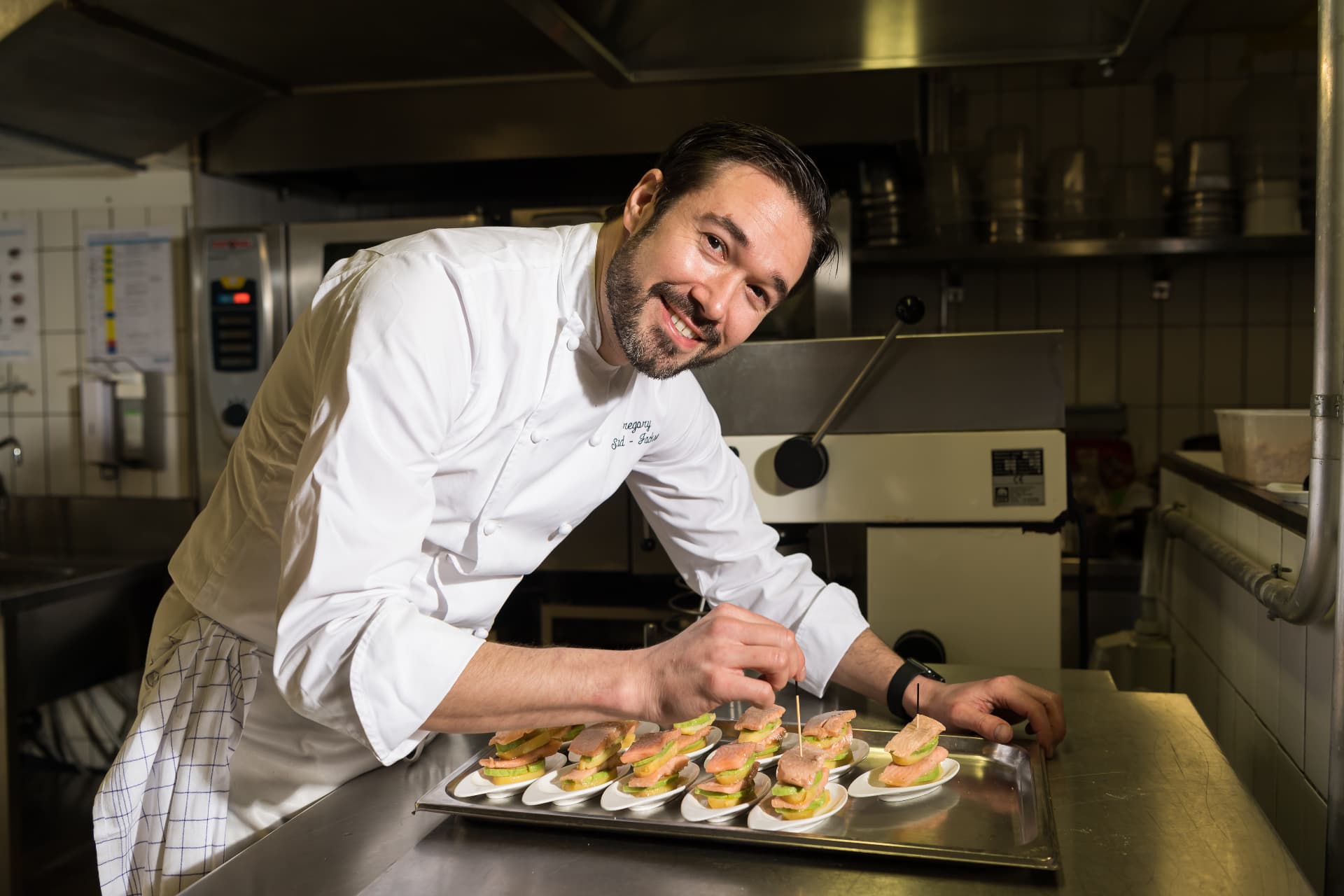 Gregory leaning over the pass, finishing a run of salmon canapés.